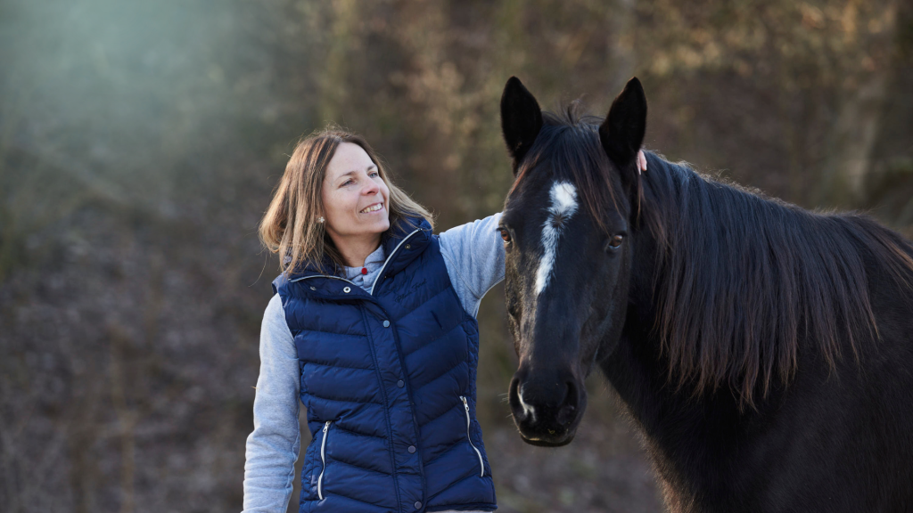 Horsebrain Coaching Denise Wiegand Frau streichelt schwarzes Pferd